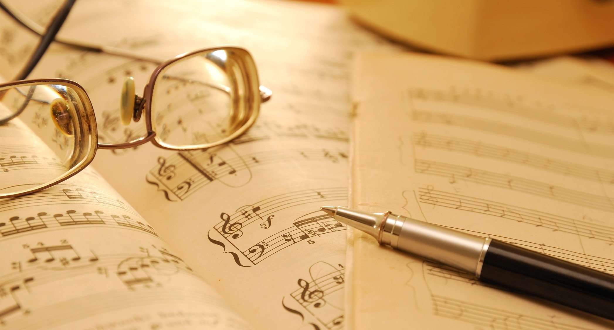Close-up of musical notes, glasses, and a pen on sheet music.