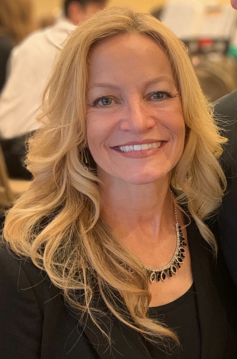 Smiling woman with blonde hair and a necklace.